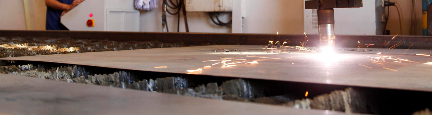 CNC plasma cutting machine processing metal sheet with sparks in industrial workshop