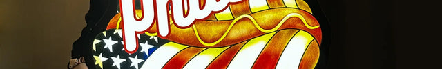 Custom illuminated sign featuring the word Phils in white script above a hot dog with an American flag design, held indoors