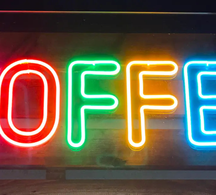 LED neon sign displaying the word 'COFFEE' in bright multicolored letters against a dark background