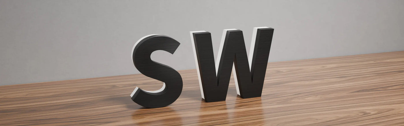 Edge-lit 3D letters 'S' and 'W' with matte black faces, unilluminated, placed on a wooden surface against a plain grey background.