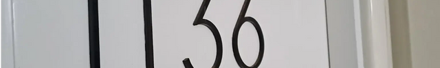 Modern black acrylic house numbers 1136 mounted on a white door